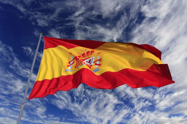 Spanska flaggan vajande i vinden mot en blå himmel med moln — Stockfoto