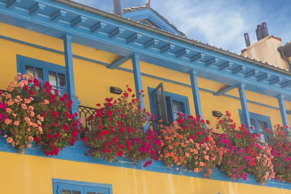 Felgekleurde huis met balkon vol met bloemen — Stockfoto