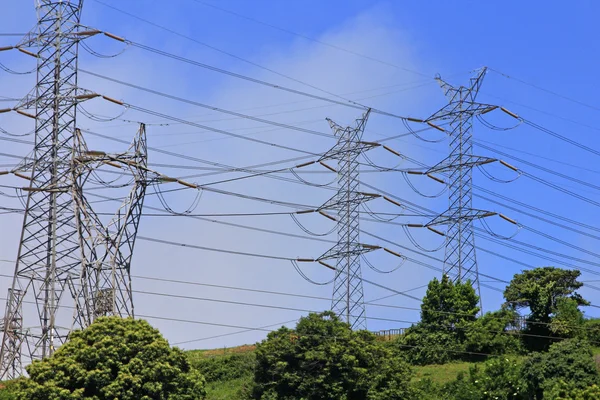 Hoogspanning elektrische torens in een groen veld — Stockfoto