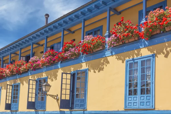 Felgekleurde huis met balkon vol met bloemen — Stockfoto