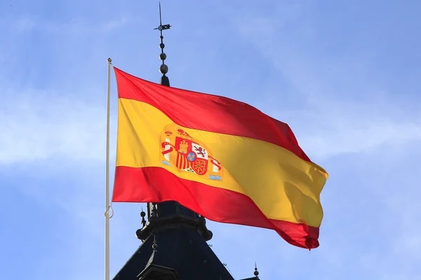 Spanska flaggan vajande i vinden mot en blå himmel — Stockfoto