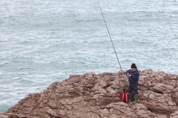 在海岸的一个拄着拐杖海钓鱼的老人 — 图库照片