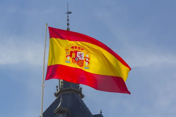 Spanska flaggan vajande i vinden mot en blå himmel — Stockfoto