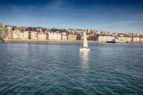 Small sailboat white sailing in front of the city of Santander, — Stock Photo, Image