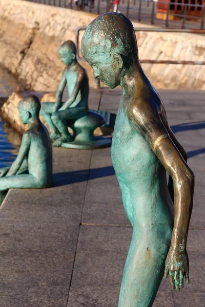 Modern figures in bronze of child jumping into the sea from a pi — Stock Photo, Image