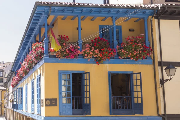 Felgekleurde huis met balkon vol met bloemen — Stockfoto