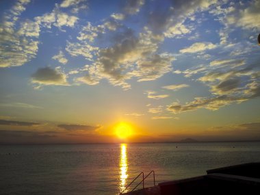 Bulutlu gün batımında sakin deniz