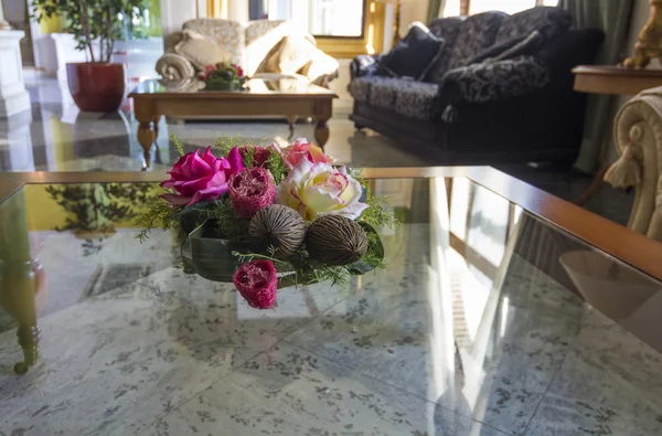 Floral center op een glazen tafel in een oude kamer — Stockfoto
