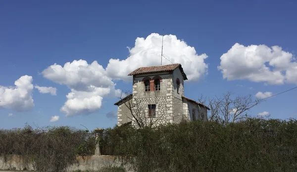 Pequena casa de pedra no campo com céu azul e nuvens — Fotografia de Stock