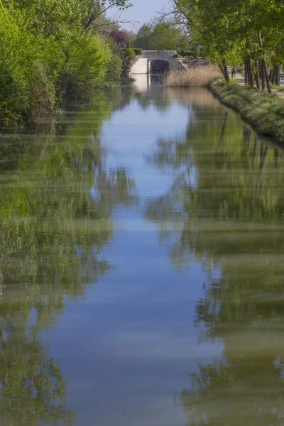 Brug over een rivier die tussen bomen met reflecties loopt — Stockfoto