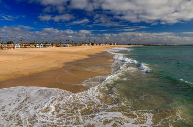 Seal Beach coastline with beachront houses and Pacific Ocean waves in a famous tourist destination viewed from the pier in California, USA