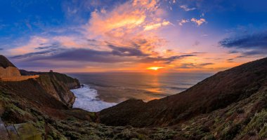 Günbatımında Kaliforniya 'daki Devil' s Slide yolunda engebeli kıyı uçurumları ve arka planda uzun süre kalmaktan Pasifik 'in ipeksi okyanus suları.