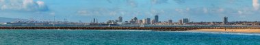 Long Beach 'teki gemilerin görüntüsü Gerald Desmond Köprüsü ve San Pedro' daki vinçler, Los Angeles limanı ve Pasifik Okyanusu dalgaları ön planda.