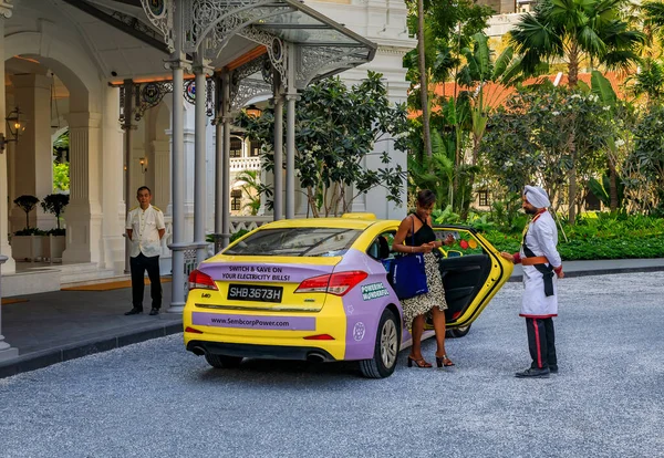 El portero sikh en uniforme ayuda a una mujer a salir de un taxi, Raffles Hotel, Singapur — Foto de Stock