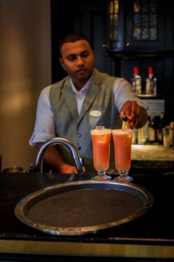 Singapur - 08 Eylül 2019: Sunucu Singapur Sling kokteylini icadıyla ünlü Raffles Hotel Long Bar 'da hazırlıyor.