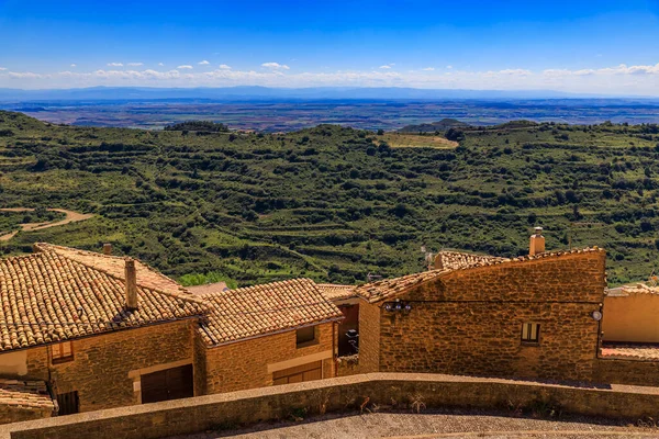 Ujue, Navarra, İspanya 'daki İglesia de Santa Maria kale kilisesi yakınlarındaki bir vadiyi çevreleyen eski taş evlerin ve tarlaların hava manzarası.