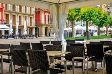 Tables at one of many outdoor cafes on historic Plaza del Castillo in Old Town Pamplona, Spain famous for running of the bulls
