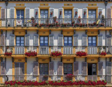 San Sebastian, Spain - June 26, 2021: Ornate house facades and metal balconies with flowers on Constitution Square in old town Donostia Basque Country