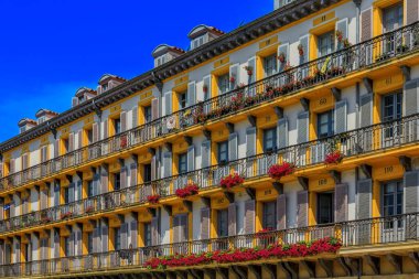 San Sebastian, Spain - June 26, 2021: Ornate house facades and metal balconies with flowers on Constitution Square in old town Donostia Basque Country