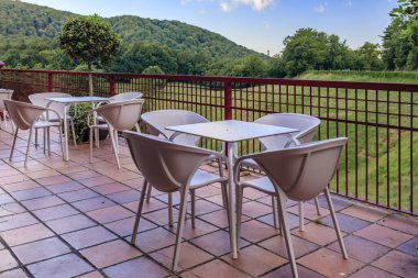 Table and chairs at an outdoor cafe with a view onto a green forest and meadow in Ultzama, Spain