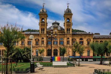 San Sebastian, Spain - June 26 2021: Ornate City Hall facade at the Alderdi Eder Gardens Park with a LGBT pride rainbow flag on the front steps