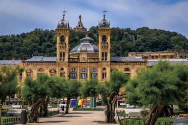 San Sebastian, Spain - June 26 2021: Ornate City Hall facade at the Alderdi Eder Gardens Park with a LGBT pride rainbow flag on the front steps