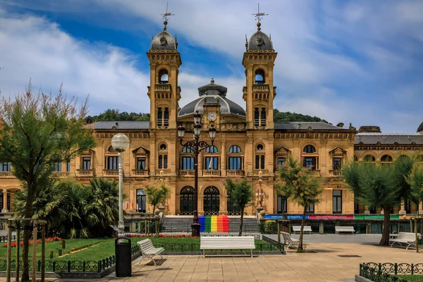 San Sebastian, Spain - June 26 2021: Ornate City Hall facade at the Alderdi Eder Gardens Park with a LGBT pride rainbow flag on the front steps