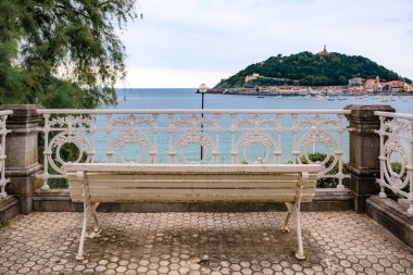 A bench overlooking Paseo de la Concha promenade and La Concha bay and Monte Urgull in San Sebastian, Spain