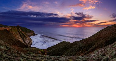Rugged coastal cliffs by the Devil's Slide trail, California at sunset with the silky Pacific ocean water from long exposure in the background