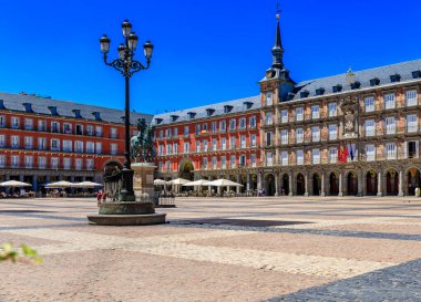 Plaza Mayor square surrounded by cafes and restaurants along the arches with Philip III statue created in 1616, Madrid, Spain