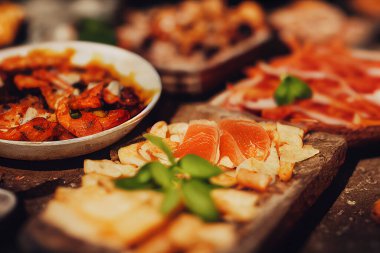 İtalyan yemekli bir masa, jambon ve peynirli şarküteri panosu, karamsar ışıklandırma, seçici odak, yemek fotoğrafçılığı ve illüstrasyon.