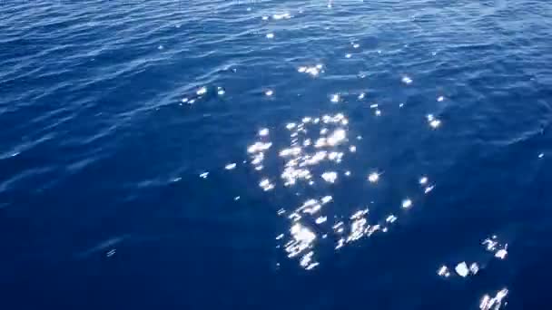 Água do mar azul com reflexos vermelhos do pôr do sol vista de um barco em movimento — Vídeo de Stock
