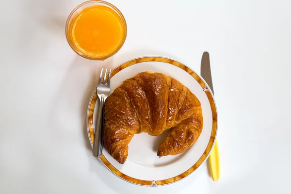 Petit déjeuner avec croissant et jus d'orange sur le plat — Photo