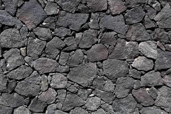 Black lava stone volcanic masonry wall — Stock Photo, Image