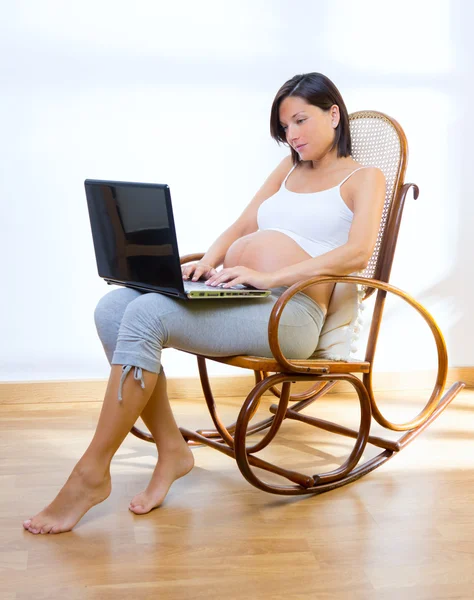 Όμορφη έγκυο γυναίκα στο σπίτι με laptop — Φωτογραφία Αρχείου