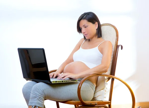 Hermosa mujer embarazada en casa con portátil —  Fotos de Stock