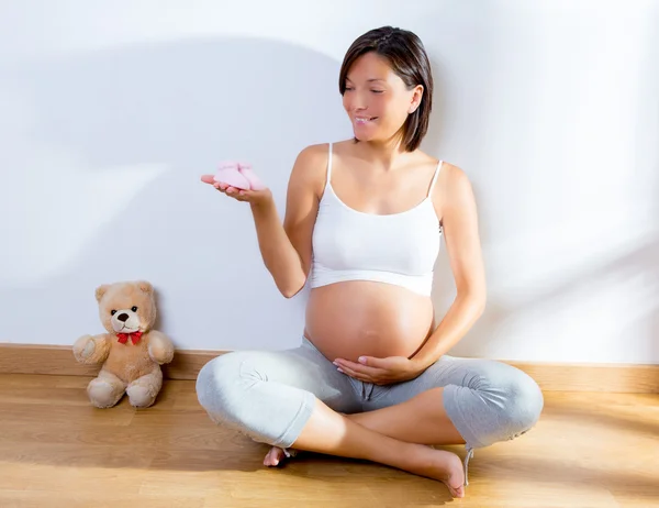 Bella donna incinta con scarpe per bambini a portata di mano — Foto Stock