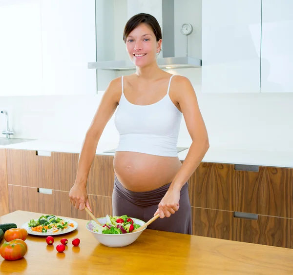 Krásná těhotná žena v kuchyni připravuje salát — Stock fotografie