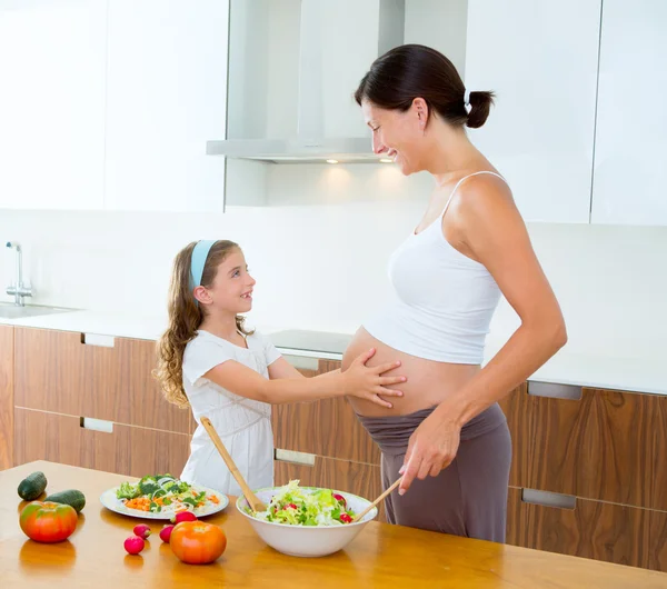 Hermosa madre embarazada con su hija en la cocina —  Fotos de Stock