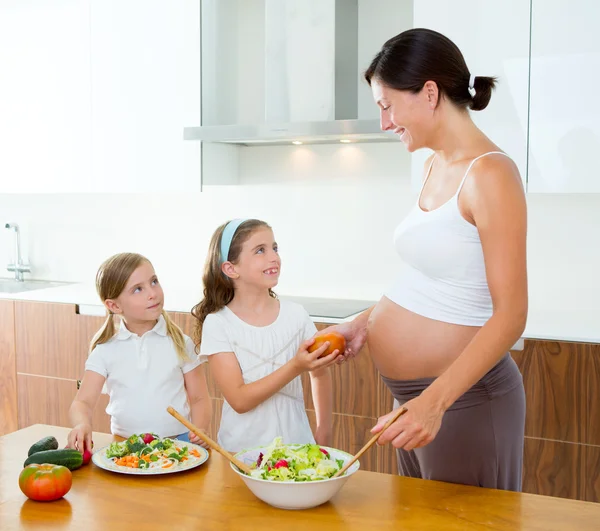 Schöne schwangere Mutter mit ihren Töchtern in der Küche — Stockfoto