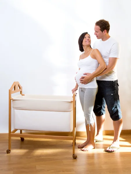 Couple with pregnant woman hug with baby cradle — Stock Photo, Image