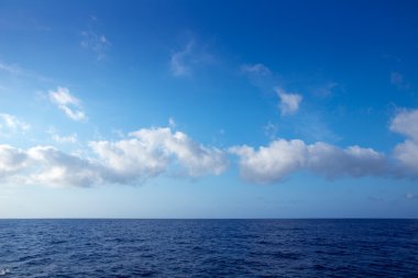 Cumulus bulutları içinde su ufuk üzerinde mavi gökyüzü