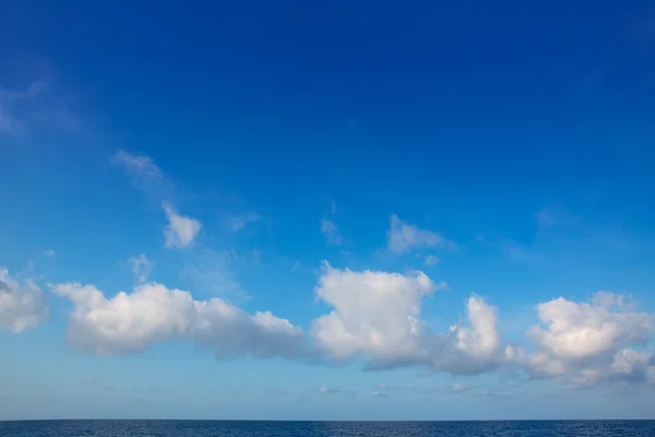 Cumulus clouds in blue sky over water horizon — Stock Photo, Image