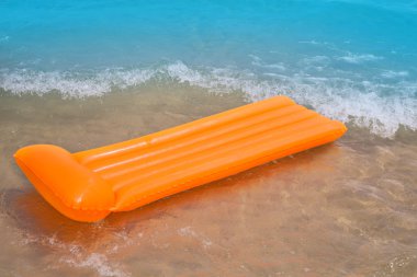 Beach shore with orange floating lounge and waves clipart