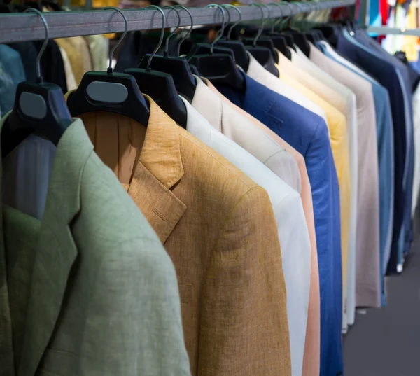 Kleurrijke mannelijke kostuums in rij in een hanger — Stockfoto