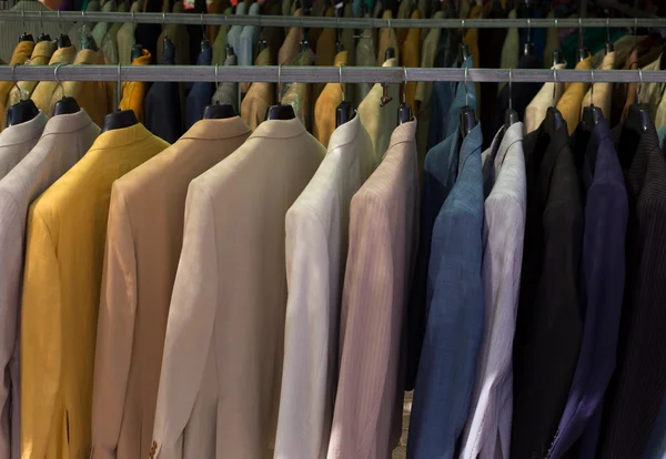 Kleurrijke mannelijke kostuums in rij in een hanger — Stockfoto