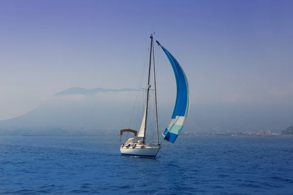Blå havet med segelbåt seglar i en dimmig kust — Stockfoto