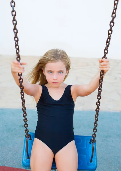 Blond dziewczynka kołysanie na niebieski huśtawka z strój kąpielowy — Zdjęcie stockowe
