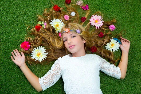 Voorjaar van blond meisje met bloemen op haar over gras — Stockfoto