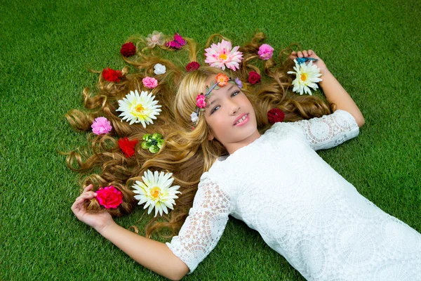 Blond spring girl with flowers on hair over grass Royalty Free Stock Photos